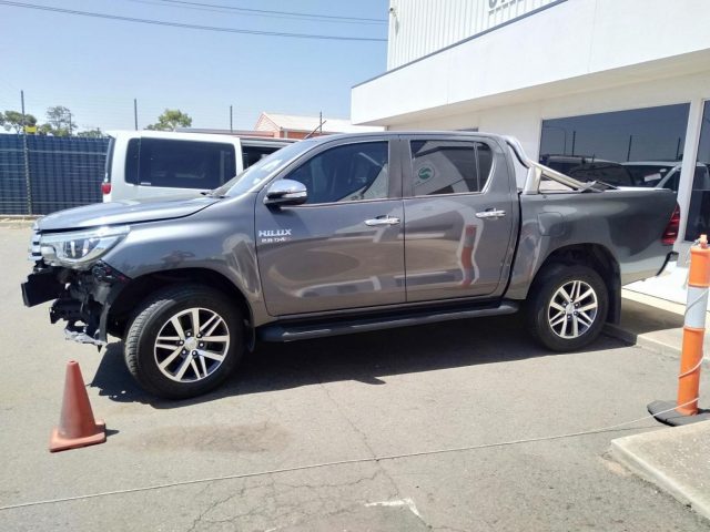 A grey Toyota Hilux with a partially dismantled front end parked outside Salisbury Auto Parts, highlighting the professional dismantlers and Toyota wreckers Adelaide specialists. 