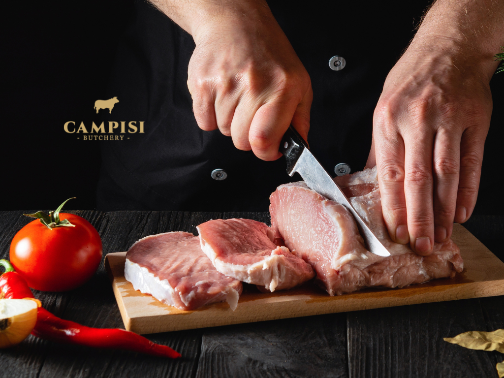 Fresh pork shoulder, belly, leg and loin cuts displayed on a butcher's counter for comparing cooking options