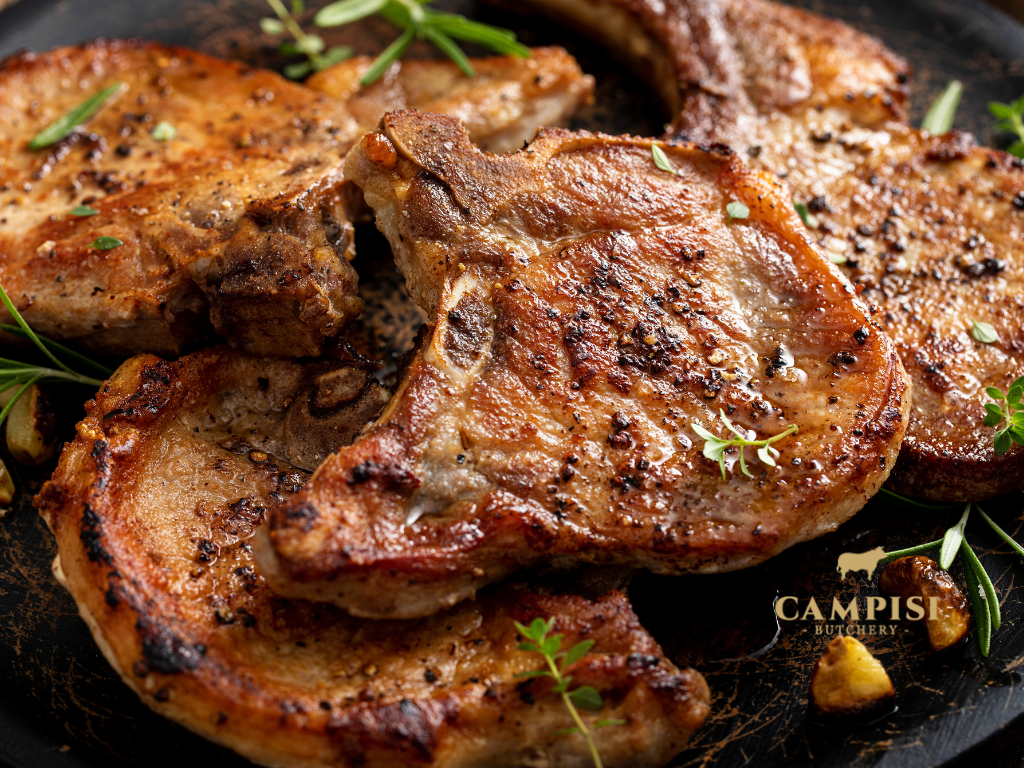 Bone-in pork chops and boneless pork loin cuts displayed on a wooden cutting board
