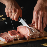 Fresh pork belly, loin chops and pork roasts arranged in a refrigerated butcher shop display