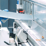 CNC press brake bending a sheet metal panel into a formed component in a fabrication workshop.