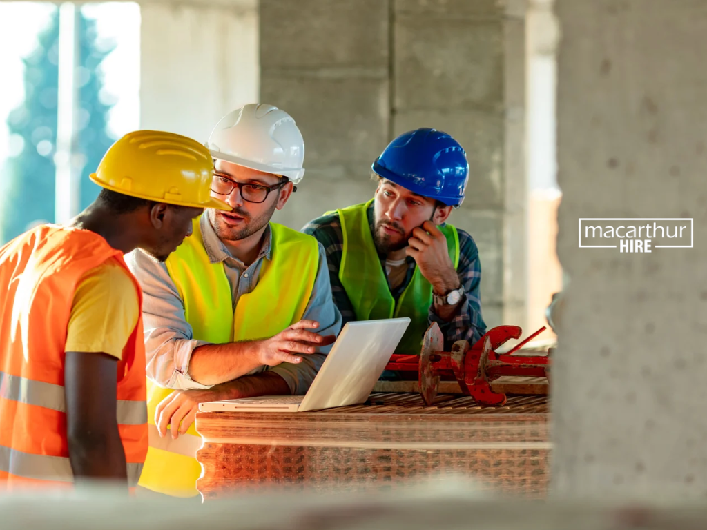 Construction business owner comparing equipment hire and leasing costs on a laptop with rental paperwork.